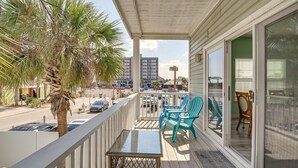 A balcony with a glass door, a palm tree, and a table.