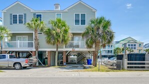 A two-story residential building with a covered front porch, a garage, and a bicycle parked inside.