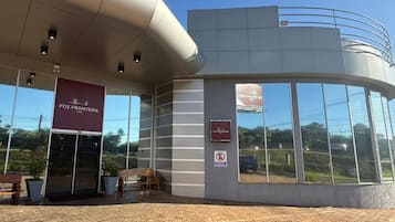 Um edifício com fachada curva, uma grande janela de vidro e uma placa com 'FOZ FRONTEIRA'.