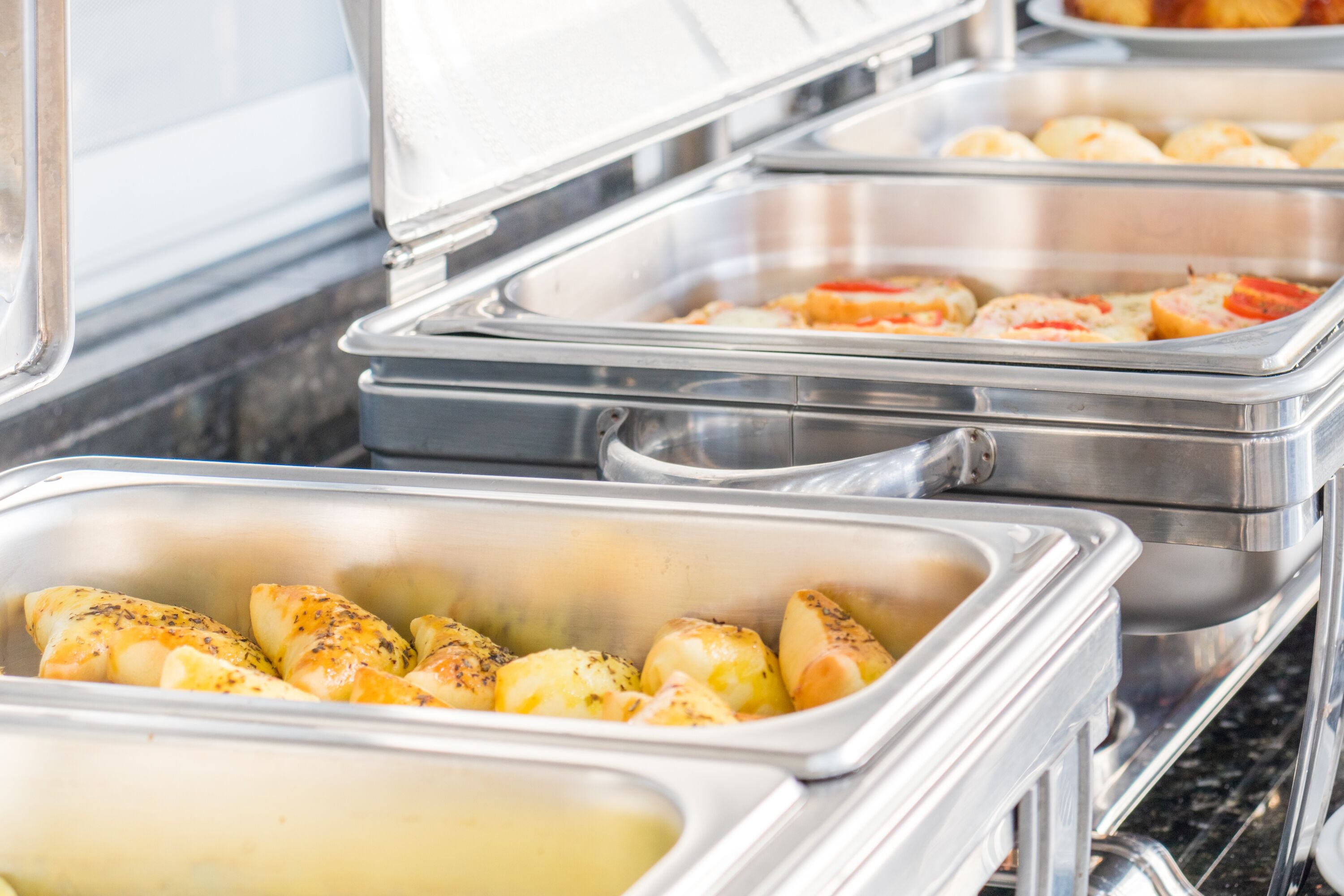 Un buffet con diversi cibi esposti in contenitori d'acciaio inossidabile.