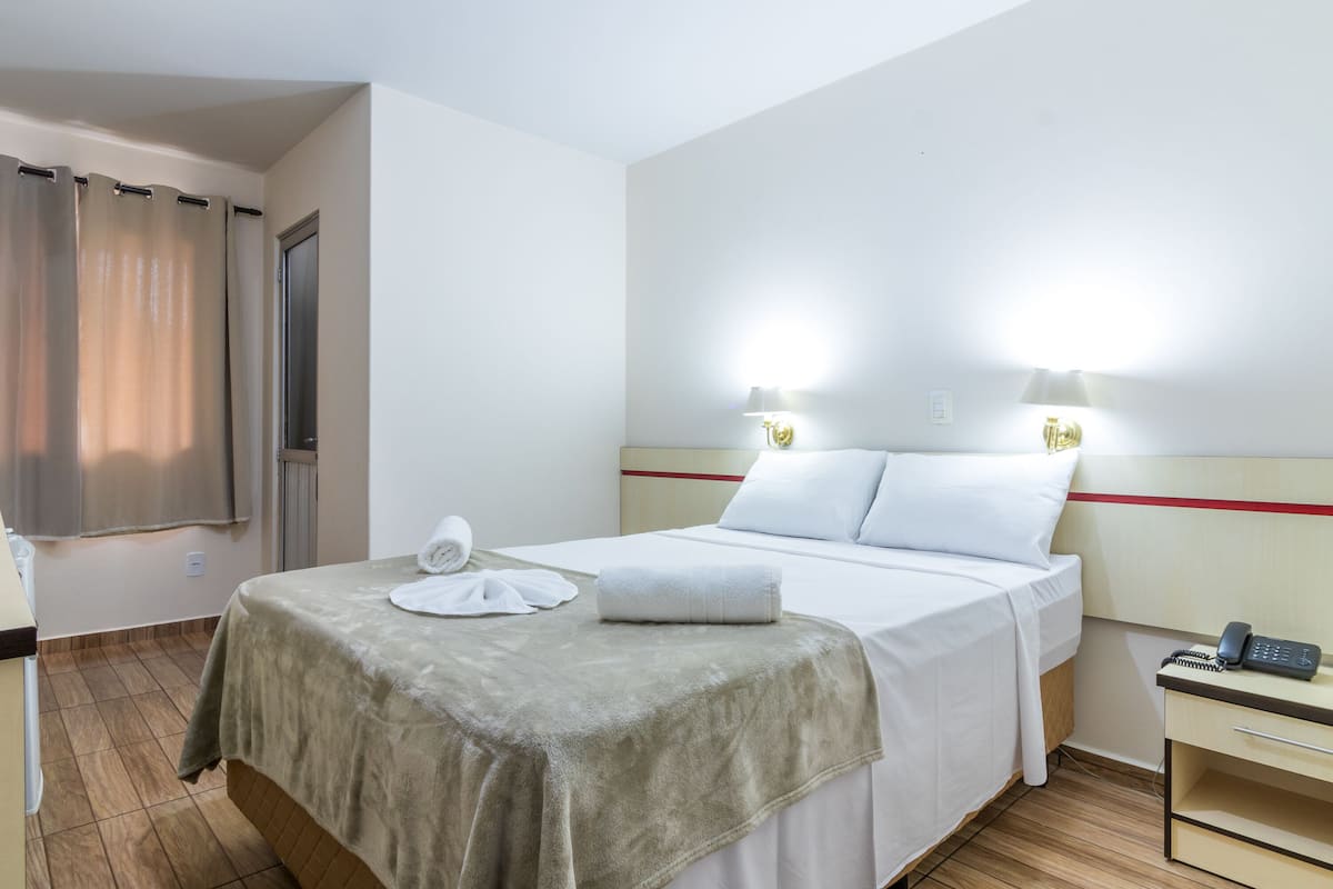 Ein Hotelzimmer mit Bett, Nachttisch und Lampe.