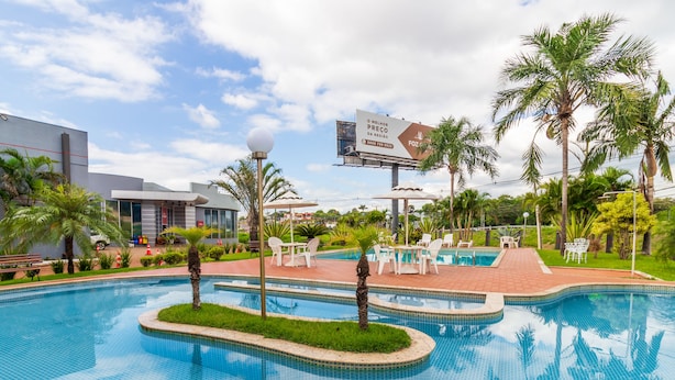 A pool area with multiple swimming pools, palm trees, and outdoor seating. - Foz Fronteira Hotel (Foz do Iguaçu)