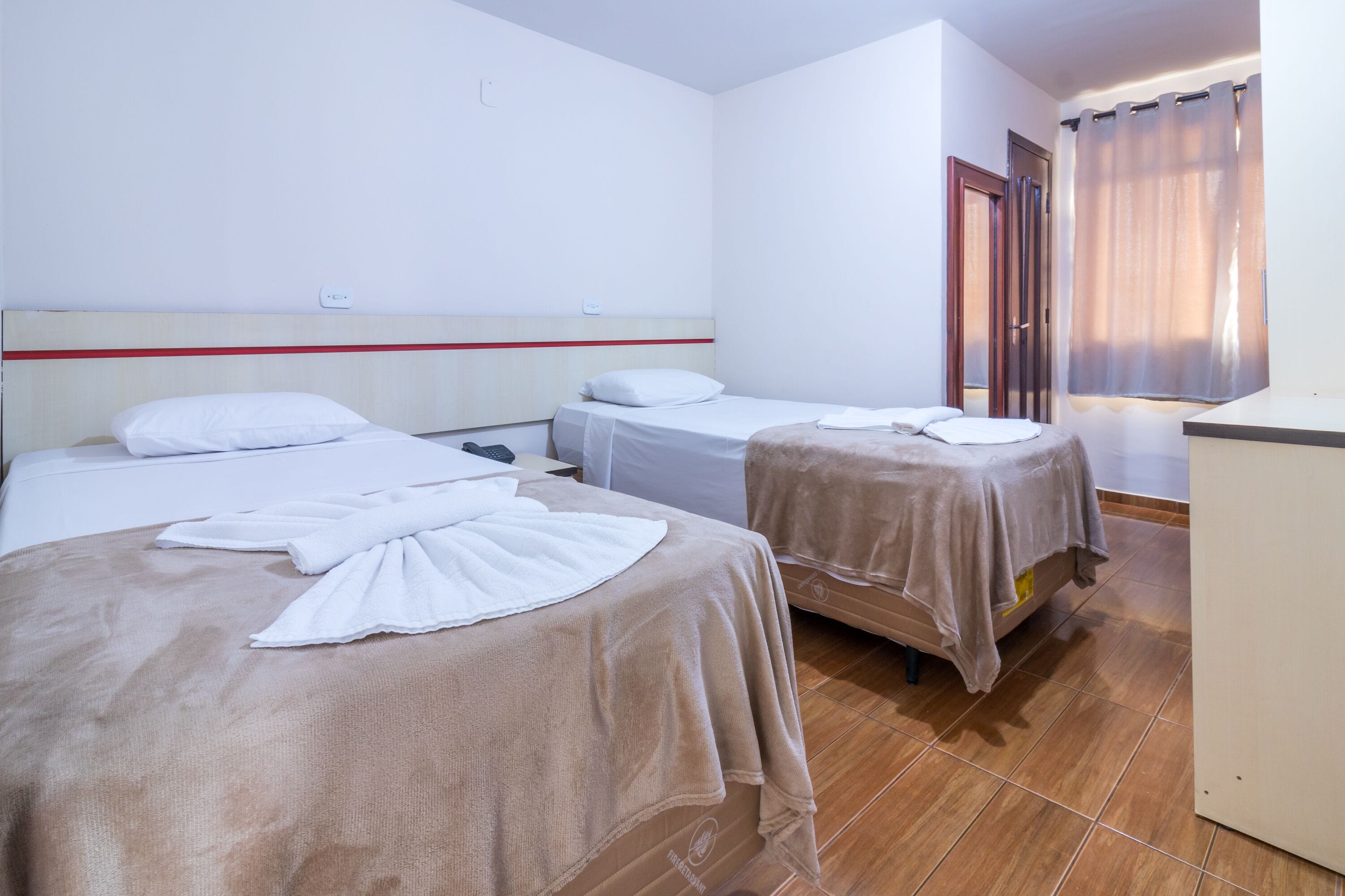 Habitación de hotel con dos camas, un escritorio pequeño y un baño con cortina de ducha.