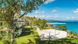 A coastal property with a pool, a tennis court, and a view of the sea. - Luxury Beachfront Condo - Hispaniola Beach 5B3 OceanView / 2 bed 2.5 bath (Sosúa)