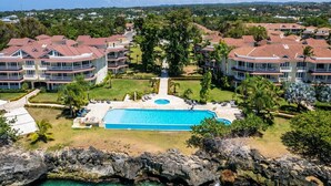 A resort with a central pool, multiple buildings, and a rocky coastline. - Luxury Beachfront Condo - Hispaniola Beach 5B3 OceanView / 2 bed 2.5 bath (Sosúa)