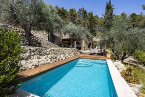 A swimming pool with a stone wall and olive trees around. - 3 bedroom villa with private pool (Mancor de la Vall)
