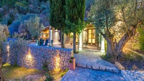 A stone-walled outdoor area with a seating arrangement and a building with a glass door. - 3 bedroom villa with private pool (Mancor de la Vall)