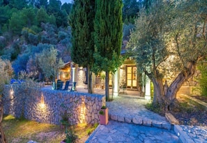 A stone-walled outdoor area with a seating arrangement and a building with a glass door. - 3 bedroom villa with private pool (Mancor de la Vall)