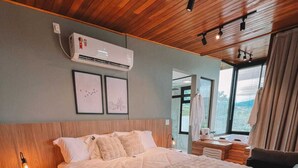 A modern bedroom with a large bed, wooden ceiling, and a view of the outdoors. - Parador do Rei (Urubici)