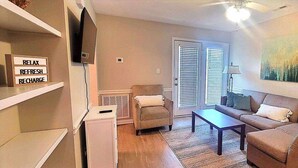 A living room with a sofa, a coffee table, a TV, and a painting on the wall.