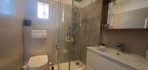 A modern bathroom with a glass-enclosed shower, a white toilet, and a vanity with a mirror. - Sea view and 50m from the beaches, 3-room apartment on the 1st floor of a villa, air-conditioned and a beautiful terrace for 4 privileged people (Fréjus)