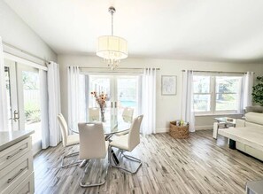 Quarto claro e espaçoso, com área de jantar, sofá e uma janela grande que oferece luz natural.