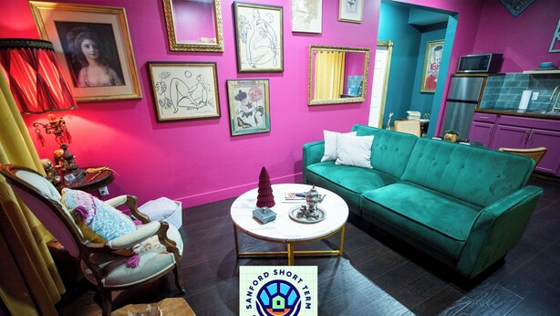 Un salon chaleureux et accueillant, avec un canapé de couleur turquoise, un fauteuil en bois et une table basse.