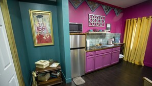 Une cuisine aux murs de couleur turquoise, avec un four à micro-ondes, des appareils en acier inoxydable et des armoires violettes.