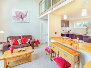 A modern living room with a sofa, coffee table, and a dining area with a wooden bench and table.