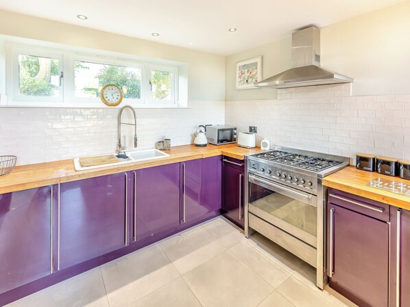 A modern kitchen with a gas stove, oven, and a window with a view of greenery. - 1 bedroom accommodation in Tenterden (Tenterden)