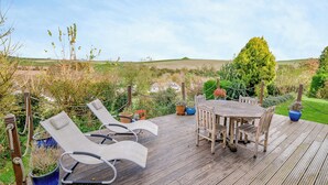 A wooden deck with a table and chairs, surrounded by potted plants and a view of a green landscape. - 5 bedroom accommodation in Martinstown, near Dorcester (Martinstown, near Dorcester)