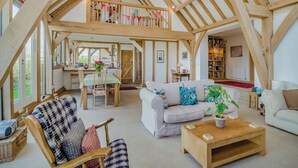 A spacious loft with high ceilings, exposed wooden beams, a dining area, and a cozy seating area with a sofa and armchairs. - 5 bedroom accommodation in Martinstown, near Dorcester (Martinstown, near Dorcester)