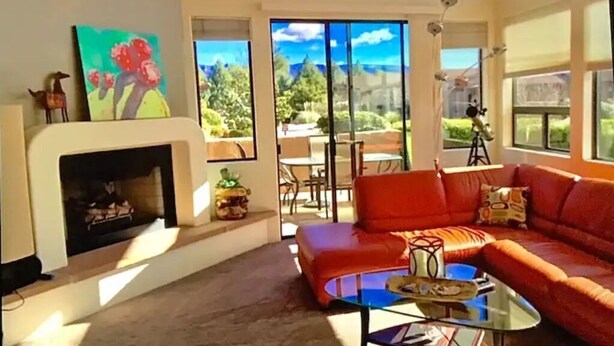Un salon avec une cheminée, un canapé rouge et une table basse en verre.