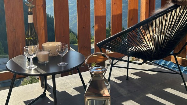 A wooden deck with a table and chairs, a candle, and a bottle of wine, overlooking a mountainous landscape. - Apt 4 ppl, balcony, near the ski runs (Modane)