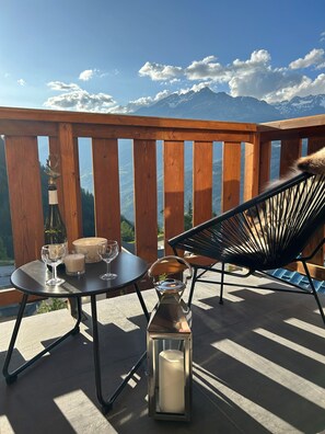 A wooden deck with a table and chairs, a candle, and a bottle of wine, overlooking a mountainous landscape. - Apt 4 ppl, balcony, near the ski runs (Modane)