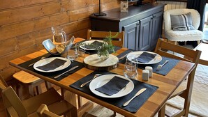 A wooden dining table set with plates, cutlery, and a glass pitcher, surrounded by wooden chairs. - Apt 4 ppl, balcony, near the ski runs (Modane)