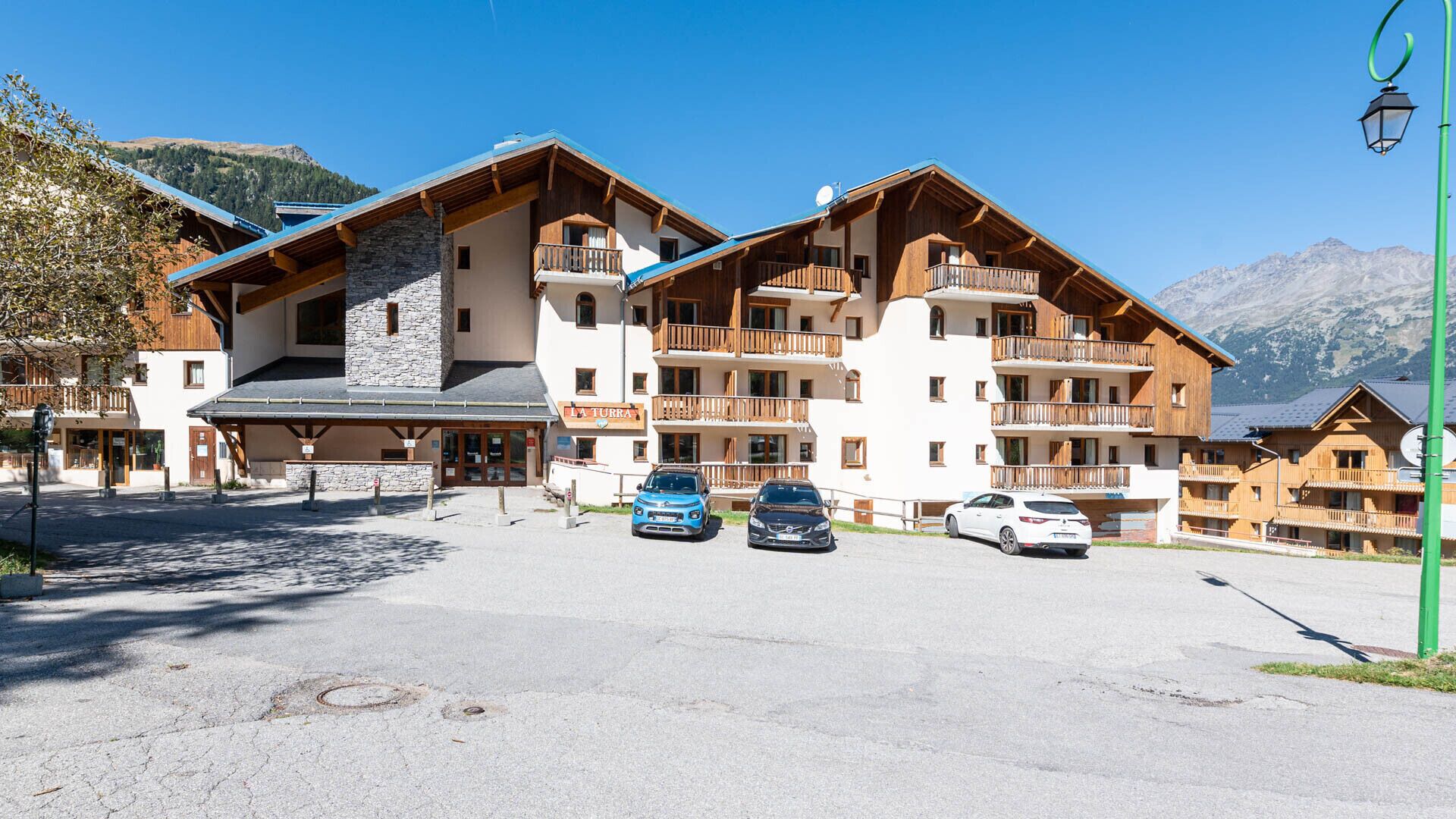 Ein mehrstöckiges Hotel mit hölzernen Balkonen und einer Steinfassade, gelegen in einer gebirgigen Landschaft.