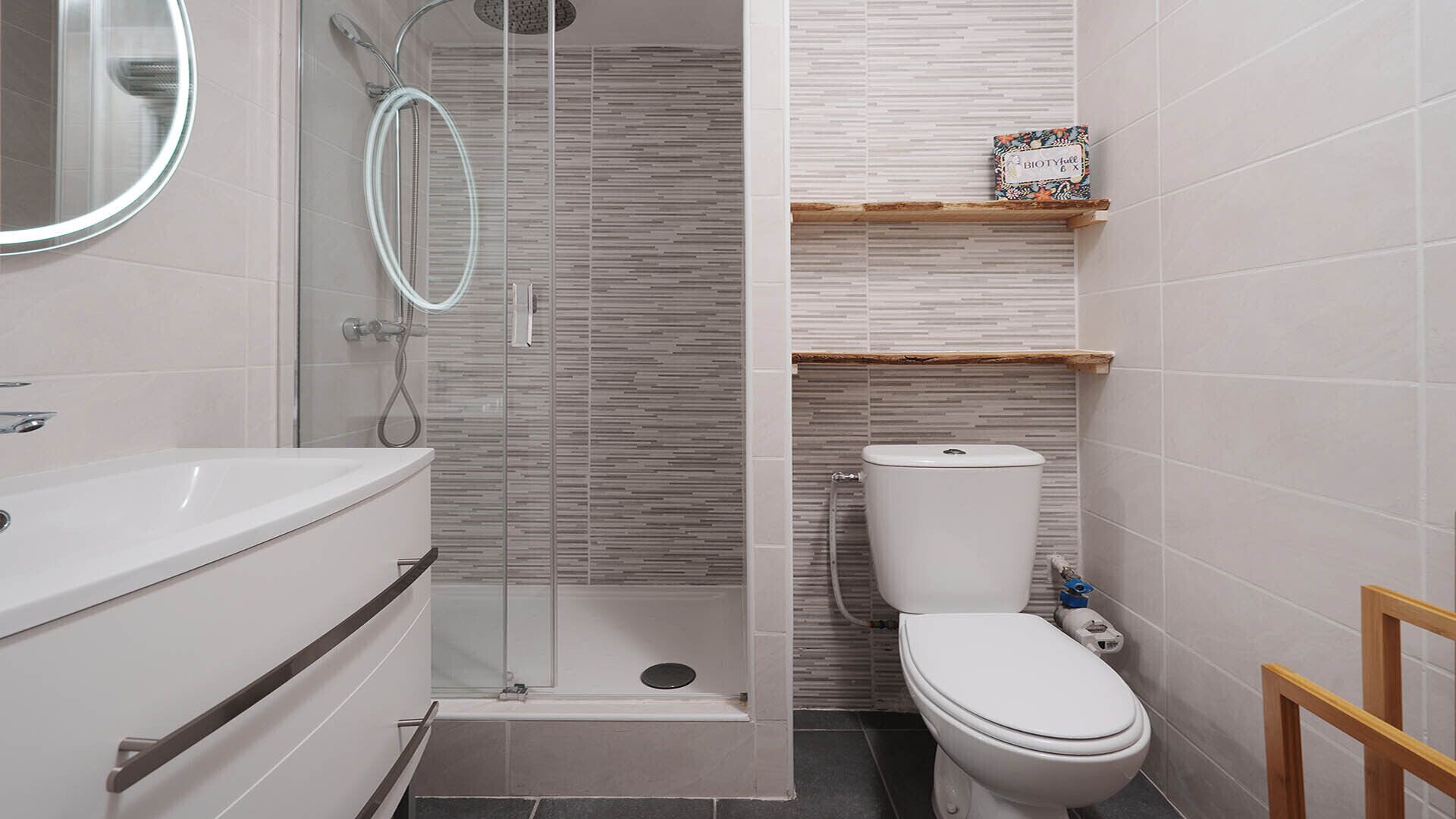 A modern bathroom with a glass-enclosed shower, a white toilet, and a vanity with a mirror.
