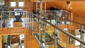 Une cabane en bois spacieuse, dotée d’un plafond haut, d’un coin repas et d’un escalier menant à un niveau supérieur.