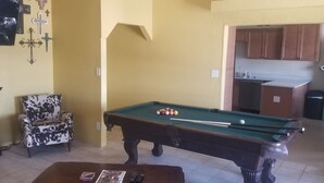 Un salon avec une table de billard, un canapé et une cheminée.