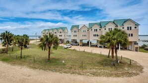 Un hotel fronte spiaggia con diversi edifici, una zona sabbiosa e palme.