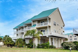 A multi-story hotel with balconies, a green roof, and surrounding greenery. - Florida Abode - Private Beach Access & Ocean Views (Alligator Point)