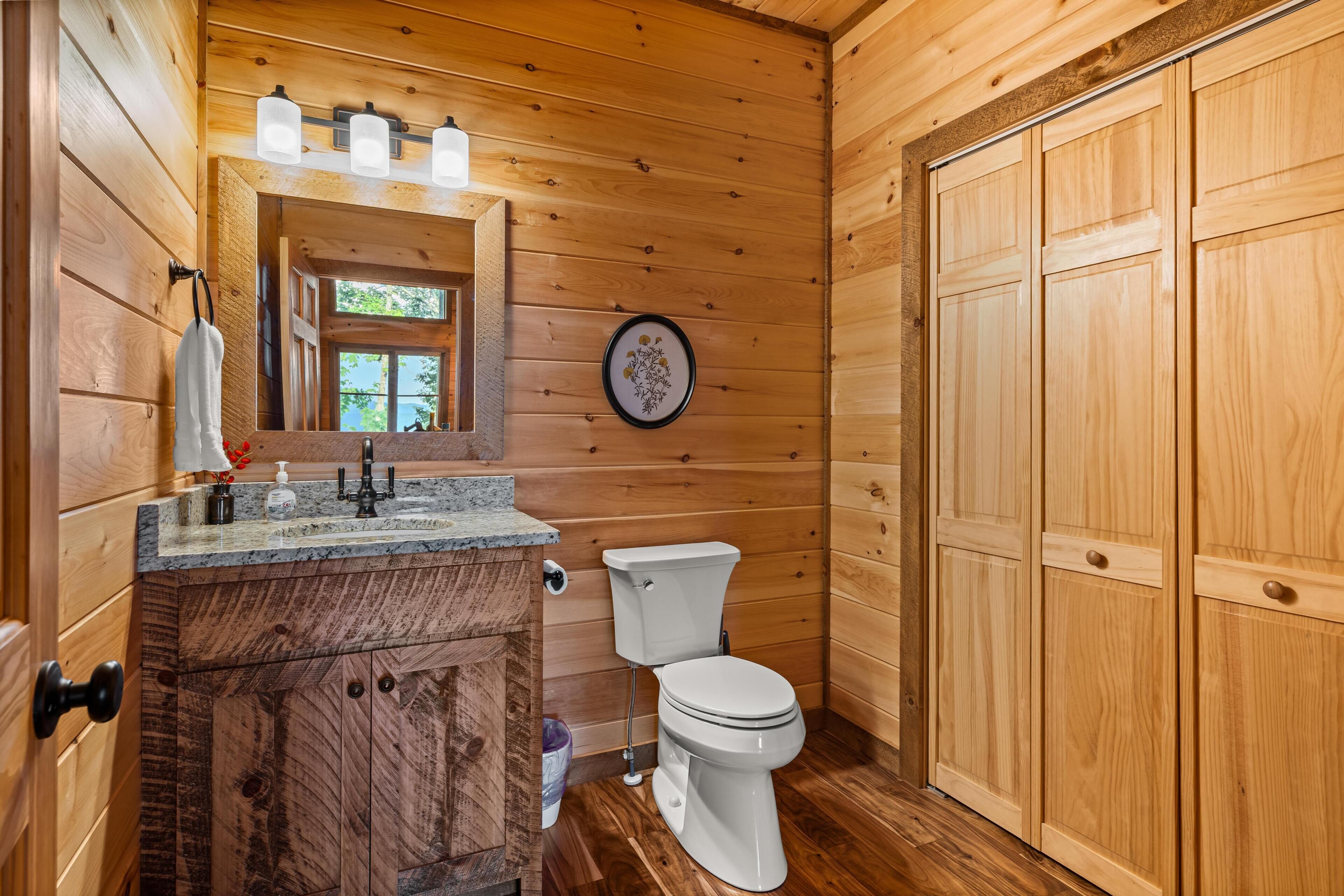 A wooden interior with a bathroom featuring a sink, mirror, and toilet.