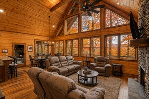 A spacious log cabin interior with a large dining area, a fireplace, and a cozy seating arrangement. - Spacious mountain cabin w/mountain views, hot tub & game room! (Cherry Log)