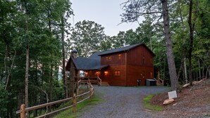 A wooden cabin with a gravel driveway, surrounded by trees. - Spacious mountain cabin w/mountain views, hot tub & game room! (Cherry Log)