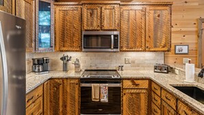 Cocina con gabinetes de madera, refrigerador de acero inoxidable, microondas, cafetera y tostadora.