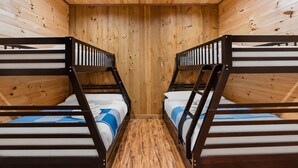 Una habitación con dos literas, paredes y suelo de madera.