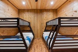 Une pièce avec deux lits superposés, des murs en bois et un plancher en bois.