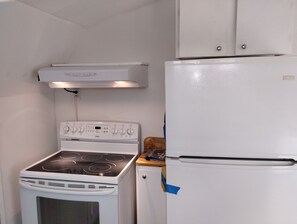 Eine kleine Küche mit einem weißen Herd, Backofen und Kühlschrank.