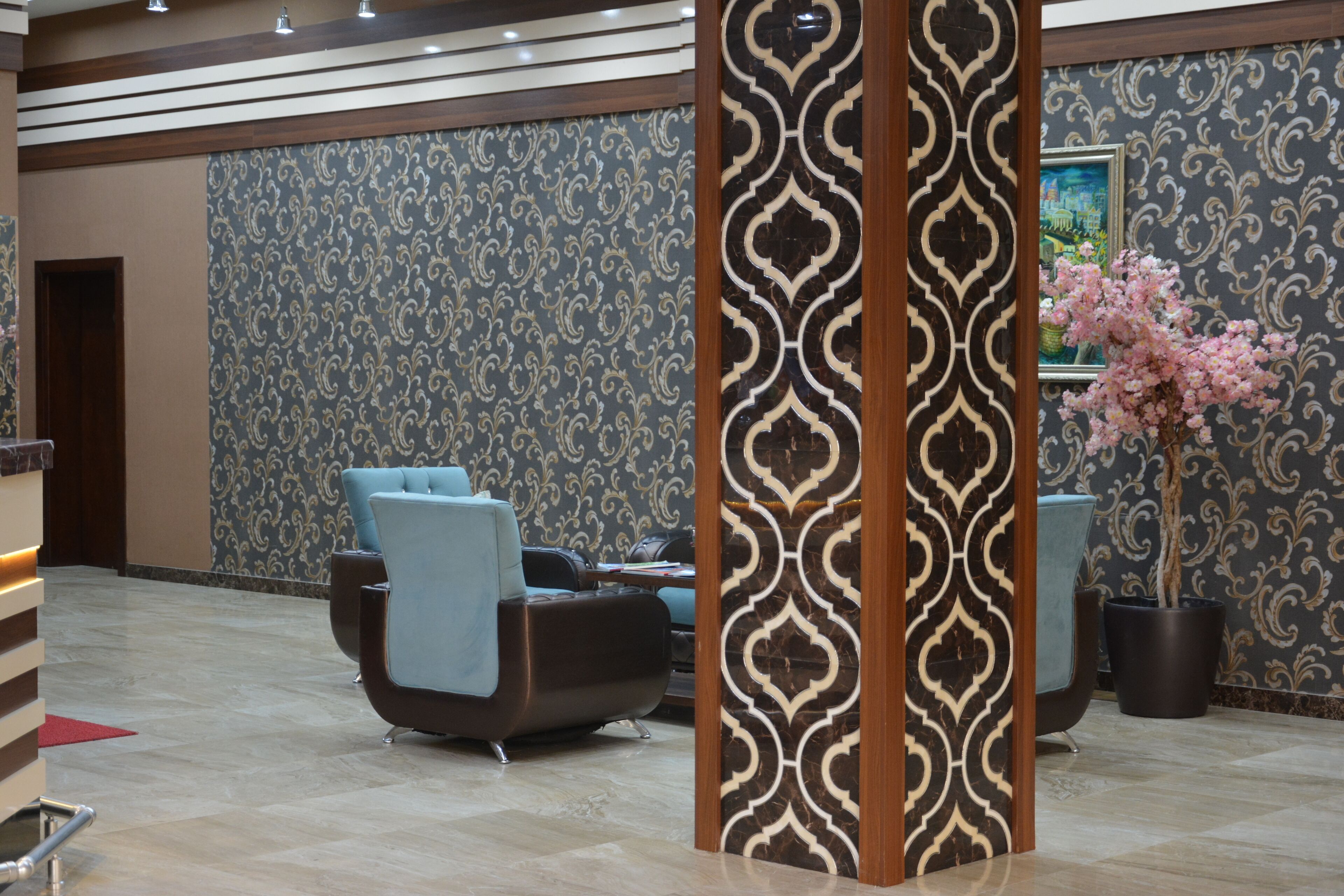 A lobby with a patterned wall, a reception desk, and a seating area with chairs.