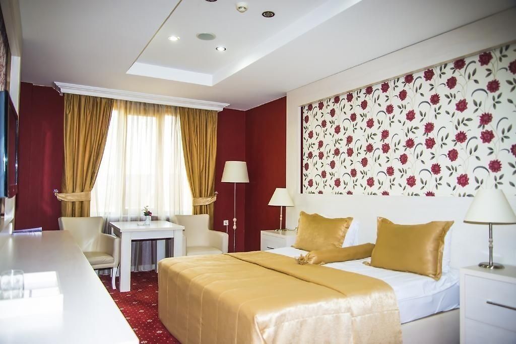 A hotel room with a bed, a desk, and a chair.