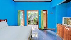 A room with a bed, a television on a wooden cabinet, and a door leading to an outdoor area with plants. - Hotel O Mustika (Negara)
