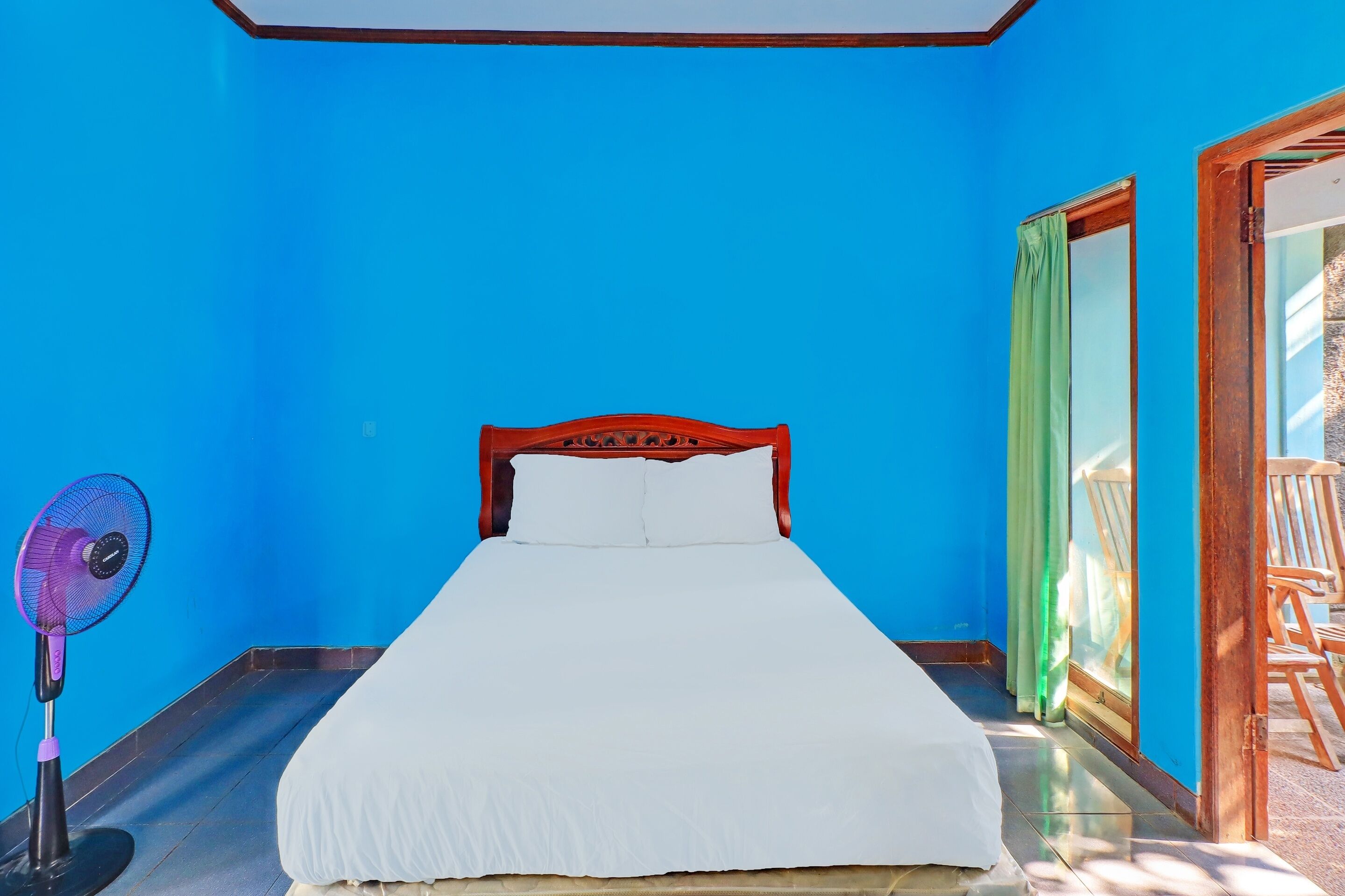 Una habitación con una cama, un ventilador y vistas al exterior.