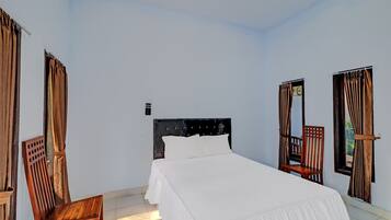 A bedroom with a bed, a wooden chair, and a window with curtains.