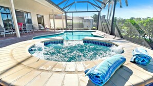 A hot tub area with a glass-enclosed patio, lounge chairs, and a pool. - Altaira - Top Location, Lake View, Pool, Spa,4 Bed (Naples)