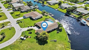 Ovenfra ses et boligområde med huse, en kanal og både.