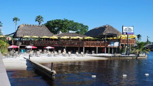 A beachfront restaurant with thatched roofs and outdoor seating. - Boaters Dream, S. Terr, Pool, Yacht Club, Boating (Cape Coral)