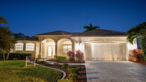 A well-lit residential property with a large garage, arched windows, and landscaped gardens. - Boaters Dream, S. Terr, Pool, Yacht Club, Boating (Cape Coral)