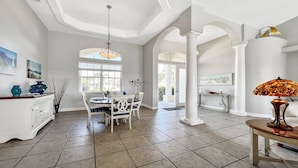 A spacious dining area with a high ceiling, white columns, and a large window providing natural light. - Boaters Dream, S. Terr, Pool, Yacht Club, Boating (Cape Coral)