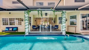 A pool area with a covered seating area, a glass partition, and a view of the interior. - Golden Globe - luxury on the canal with pool/spa (Cape Coral)